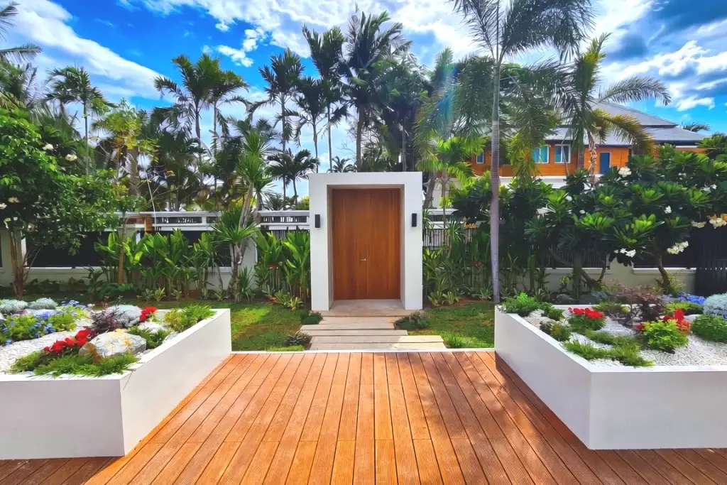 Luxury tropical landscape entrance with wooden deck, modern white planters and lush gardens completed in 2024 at Na Jomtien, Pattaya, Chonburi