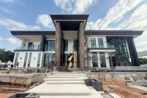 Modern luxury villa under construction featuring dramatic travertine marble entrance pillars, grand entrance staircase, and contemporary black and white architecture in Pattaya, Thailand, Chonbur Province