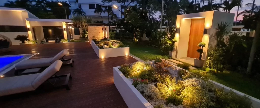 Beautifully illuminated night landscape with wooden deck, lounge chairs and garden lighting – CSP Construction Jomtien