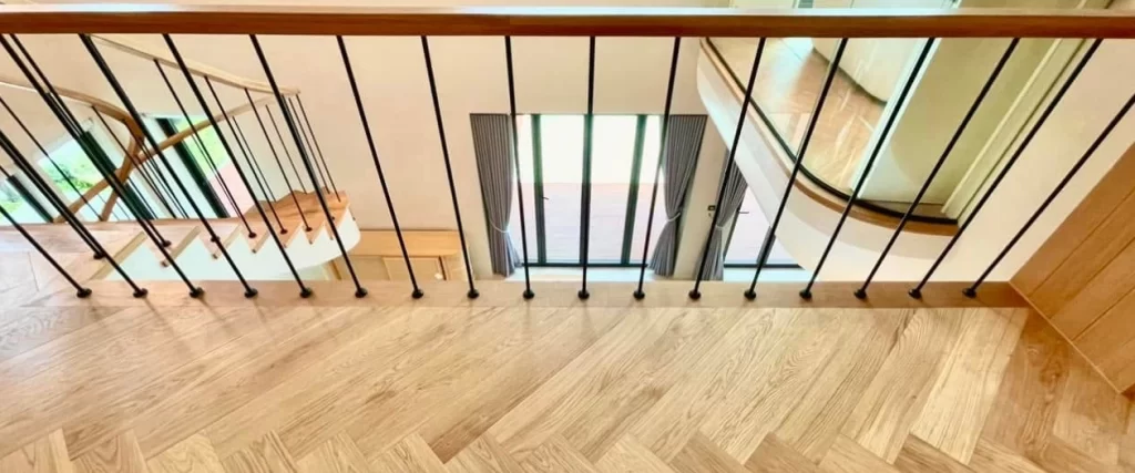 Premium natural oak herringbone floor with custom black steel handrail staircase detail by CSP Construction