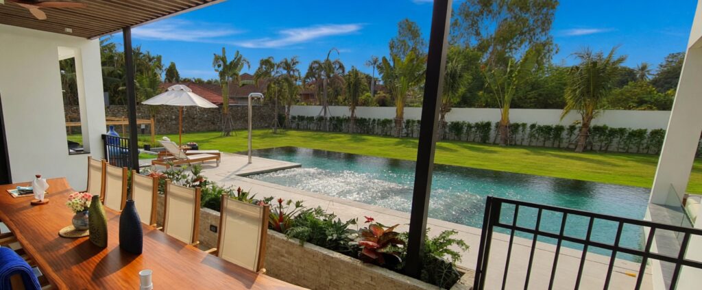 Outdoor dining area overlooking a stunning infinity pool and tropical garden in Maprachan Pattaya