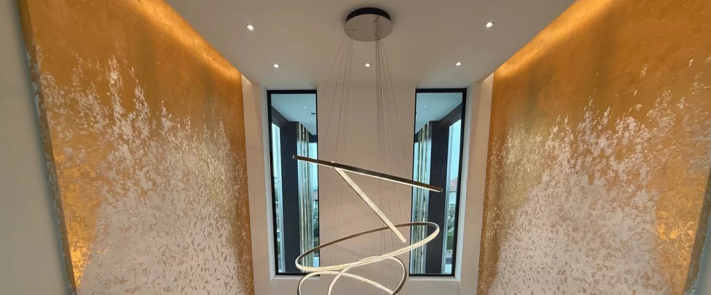 Luxury modern interior with textured gold walls, dramatic sculptural chandelier and floor-to-ceiling windows at Phoenix Golf Club by CSP Construction