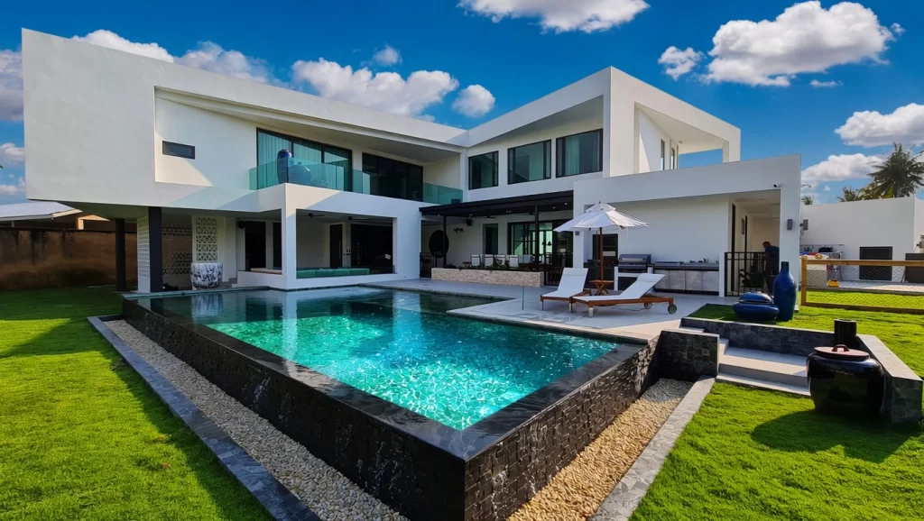 Luxurious infinity swimming pool with black tiled border and sun loungers on the manicured lawn at Maprachan Villa, Pattaya